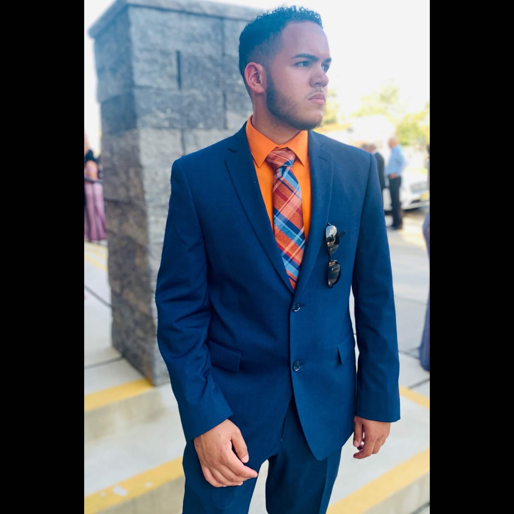 Raf (Rafmeta) portrait in a navy suit Raf (Rafmeta / @rafmeta) in a navy suit, orange shirt, and plaid tie